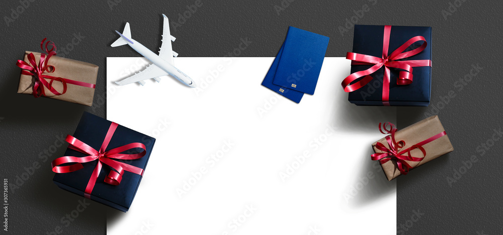 Fototapeta premium Christmas travel planning. Traveling as gift. White blank model of passenger plane and gift box on background. Top view or flat lay. Copy Space.