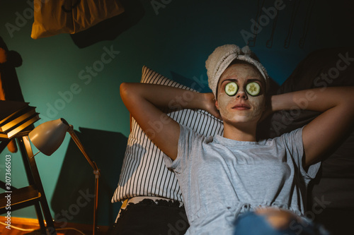 woman laying on bed applied cosmetic face mask