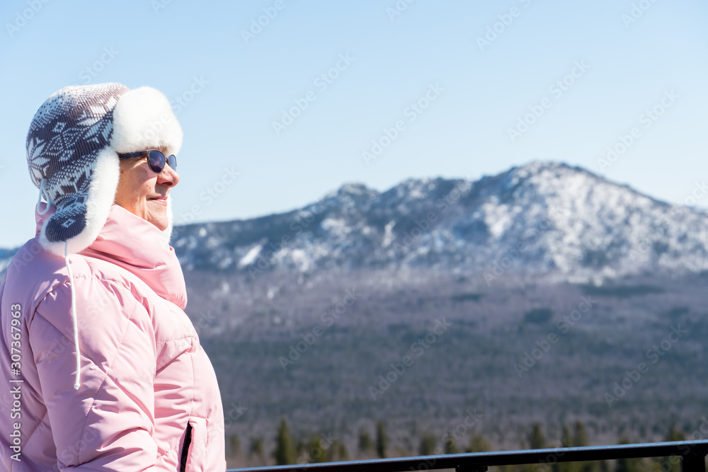 Naklejka premium aged grandmother walks on snowy beauties. In the background are snowy mountains and fresh air.
