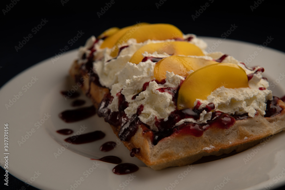 waffle topped with whipped cream, sauce and fruit waffle topped with whipped cream, sauce and fruit
