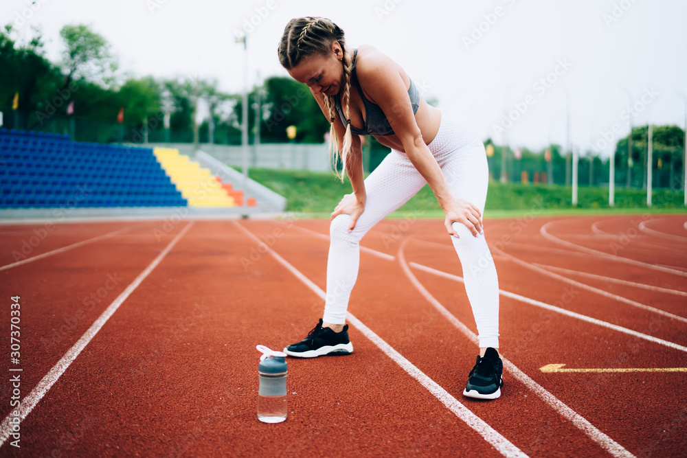 Adult sporty female taking rest training in stadium Adult sporty female taking rest training in stadium