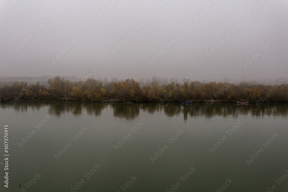 Moody shot of calm river with heavy fog