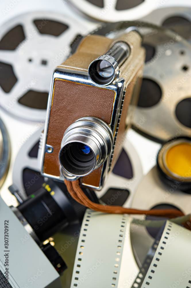 Vintage movie cameras lie on the background of reels with film strip.
