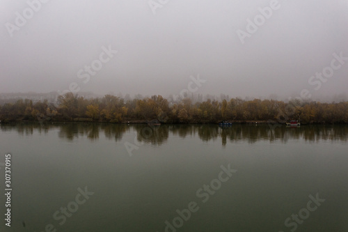 Moody shot of calm river with heavy fog