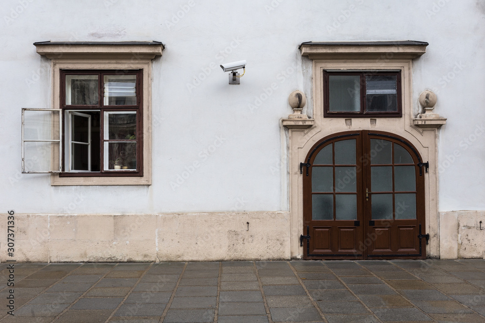 Two large closed doors next to an open vintage window with stone ground Two large closed doors next to an open vintage window with stone ground