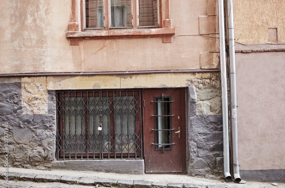 Aged old building facade with window and metal rain pipes. Historical city elements. European architecture Aged old building facade with window and metal rain pipes. Historical city elements. European architecture