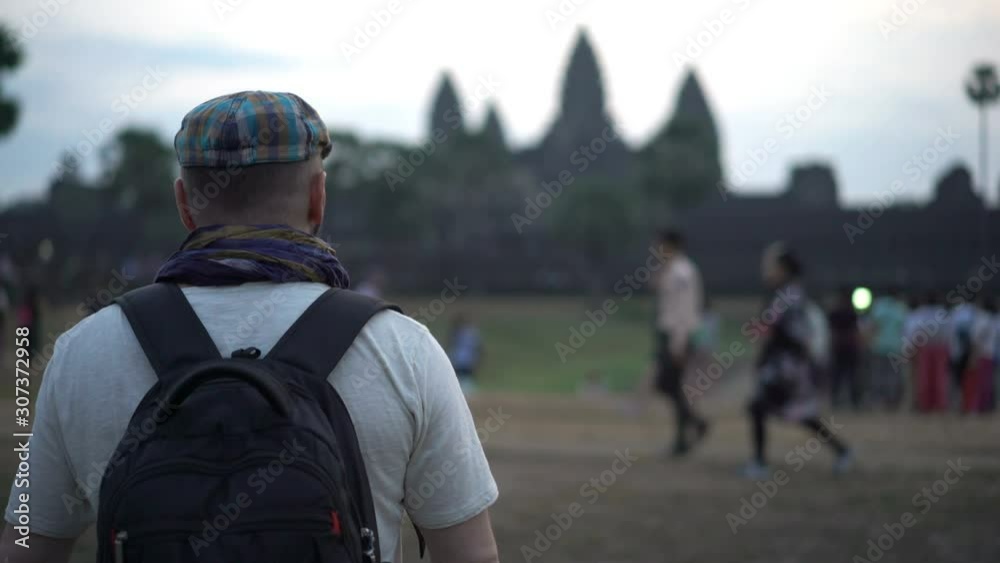 Man looking at ancient Angkor Wat complex temple ruins in Cambodia Man looking at ancient Angkor Wat complex temple ruins in Cambodia