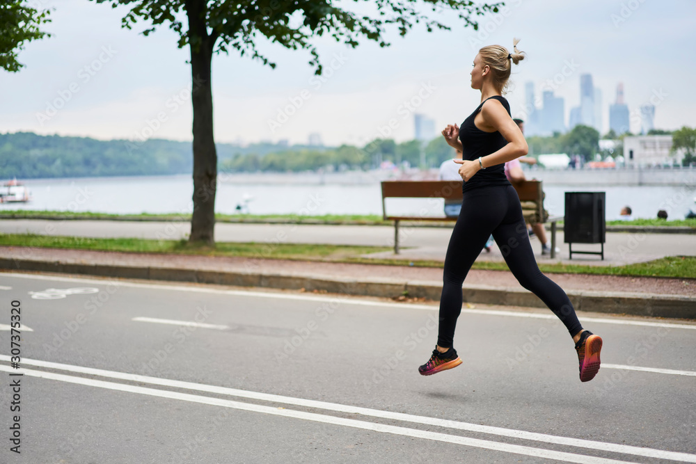 Calm confident athlete running along waterfront in park Calm confident athlete running along waterfront in park