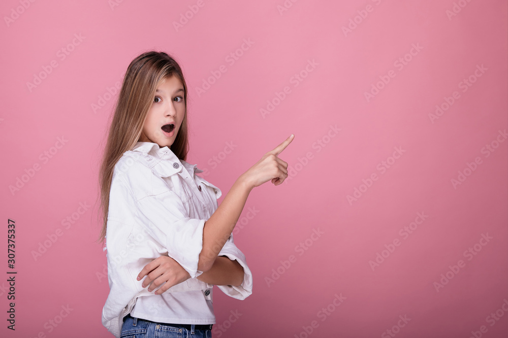 The pretty girl opened her mouth in surprise and points a finger to the side. The pretty girl opened her mouth in surprise and points a finger to the side.
