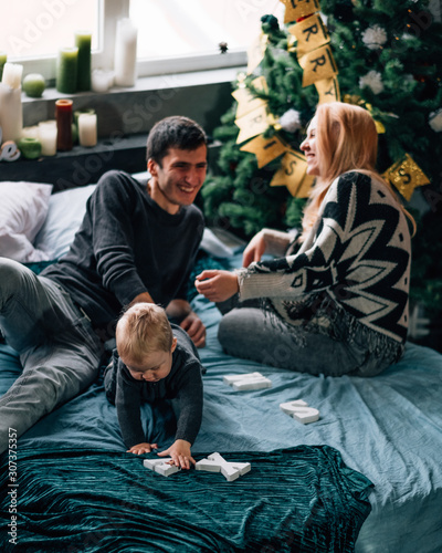 Portrait of Family Mom Dad with One Little Kid Playing in Room Decorated in Christmas Theme
