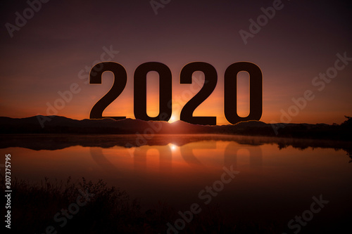 Silhouette word 2020 behind the mountain lake at golden sunrise and beautiful blue sky. Concept for vision year 2020. 