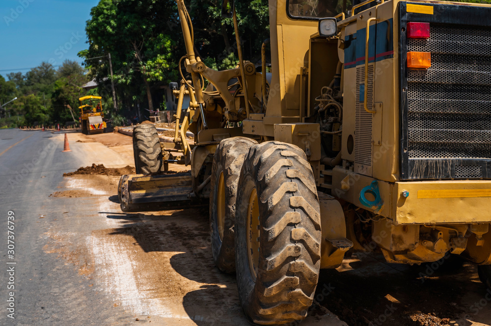 Grader is working on road construction. Grader industrial machine on construction of new roads. Heavy duty machinery working on highway. Construction equipment. Compaction of the road.