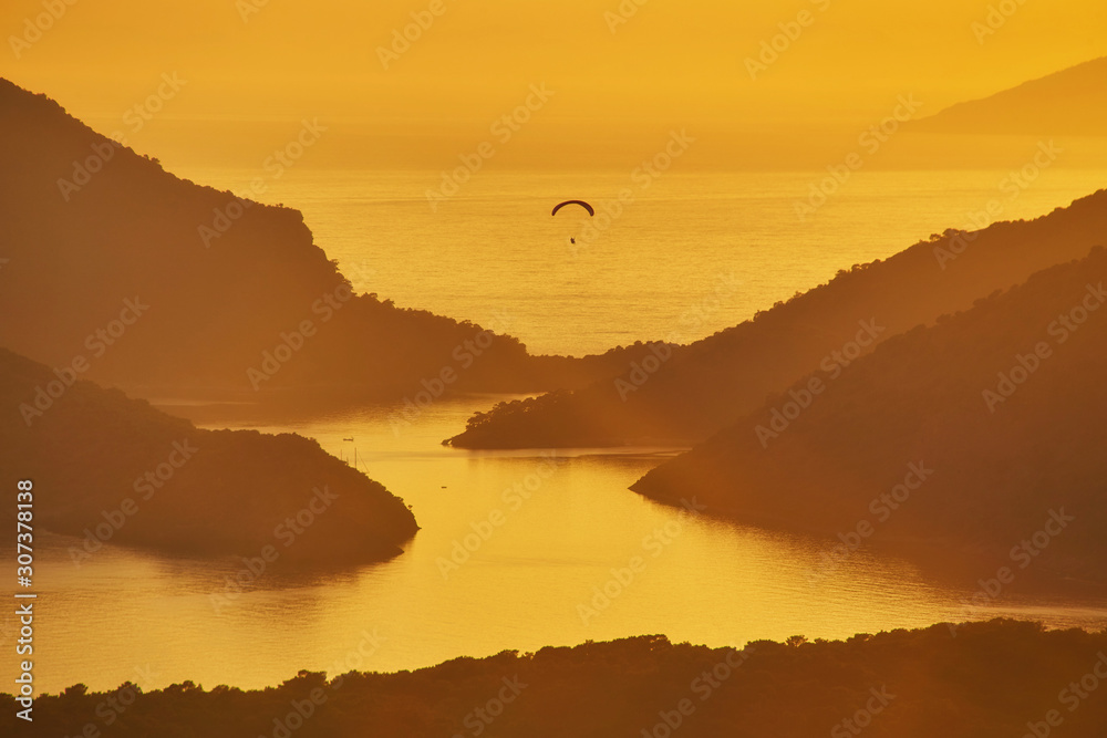 An unidentified paraglider flying at sunset over Blue lagoon in Oludeniz,