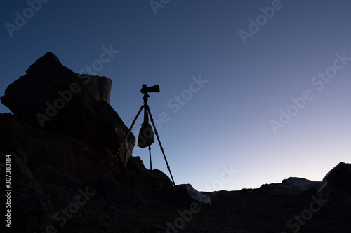 the silhouette of the tripod with the camera in the mountains at dawn