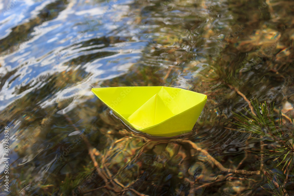 yellow paper boat floating on the water in the lake, the concept of travel, the idea of undertakings in business