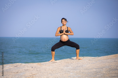 pregnant woman yoga pose on the beach sunset