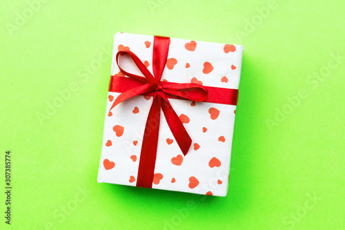 Gift box with red ribbon and heart on green background, top view with copy space for text © sosiukin