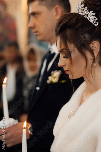Spiritual couple, bride and groom holding candles during wedding ceremony in christian church, emotional moment during ceremony for man and woman. Newlyweds in the church. Church religious details.