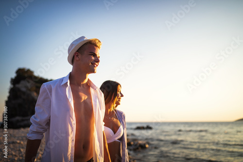Beautiful young people in love walking. Couple on beach at sunset summer vacation