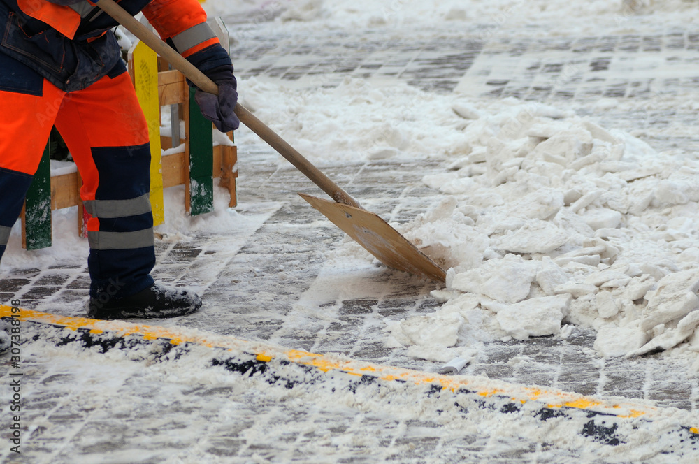 working in an orange uniform removes snow with a wooden shovel working in an orange uniform removes snow with a wooden shovel