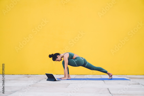 Fototapeta Naklejka Na Ścianę i Meble -  Woman practicing yoga with tablet