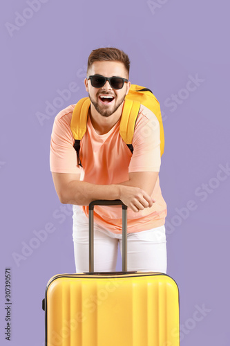 Young male tourist with luggage on color background © Pixel-Shot