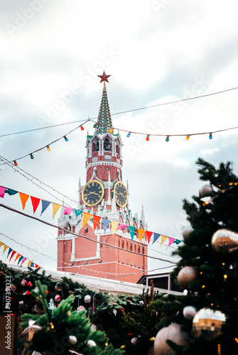 Kremlin clock tower on red square in winter, fir branches with lanterns and balls,