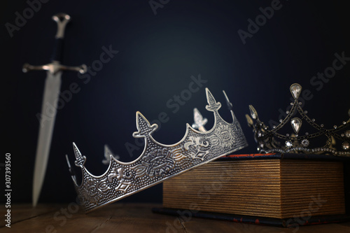 Schilderij op canvas low key image of beautiful queen/king crown over antique book next to sword