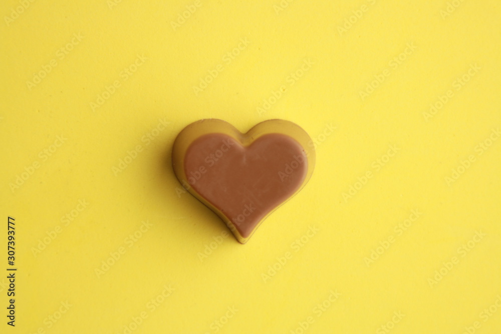 Chocolate bonbon with heart shape in color background Chocolate bonbon with heart shape in color background