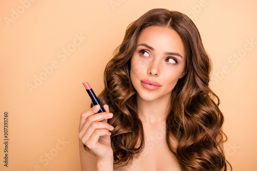 Close up photo of charming girl hold pomade try check think about new shine effect of lips stick isolated over pastel color background
