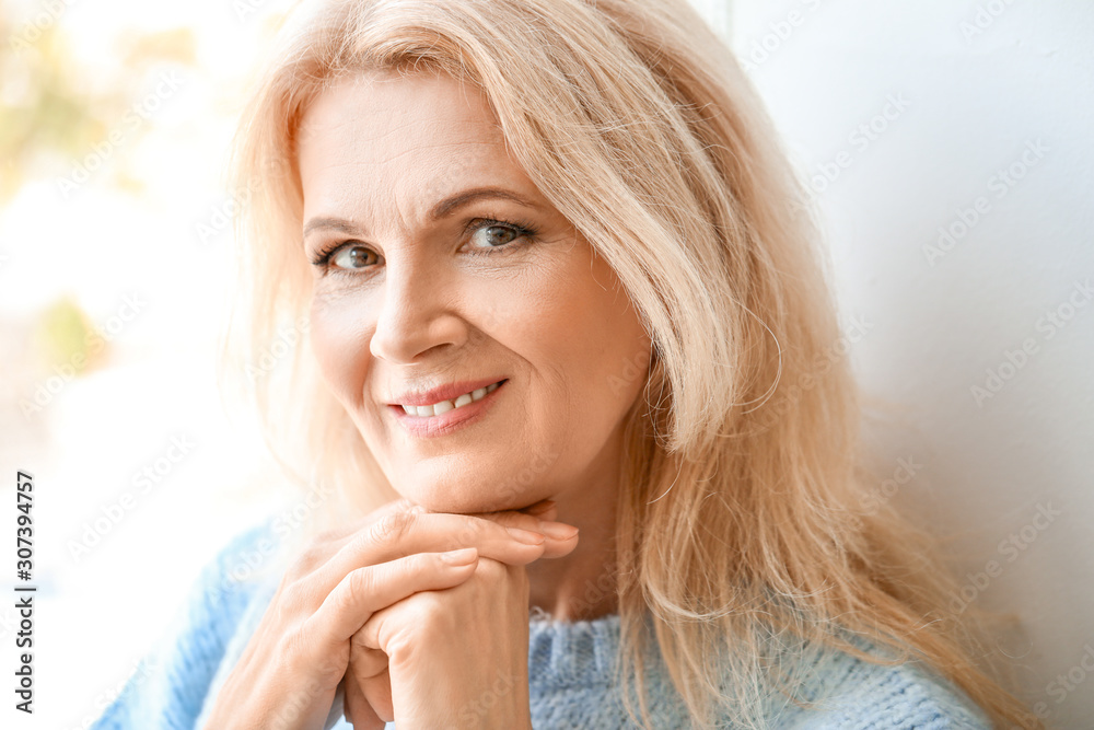 Portrait of beautiful mature woman near window Portrait of beautiful mature woman near window