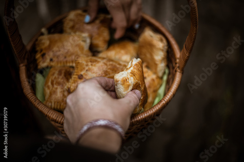 A man and woman hand grabbing home made meat patty from a basket. Basket full of home made meat patty. 