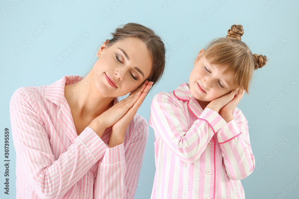 Portrait of sleepy mother and daughter in pajamas on color background Portrait of sleepy mother and daughter in pajamas on color background
