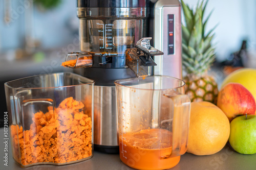 Making fruit juice with juicer machine in home kitchen, healthy eating lifestyle concept photo