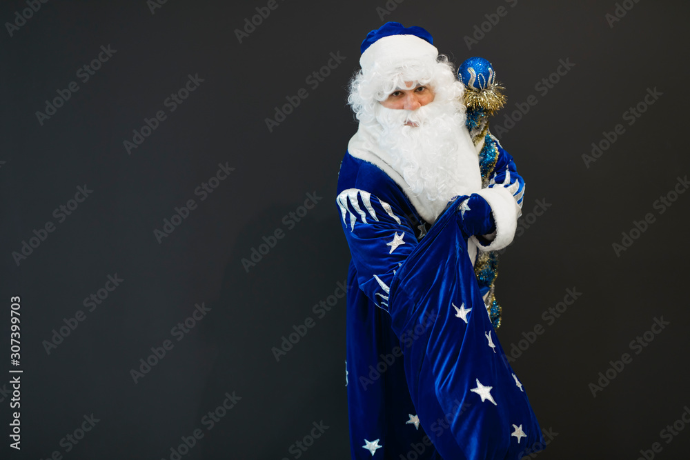 Happy blue Santa take a gift from his sack on black background