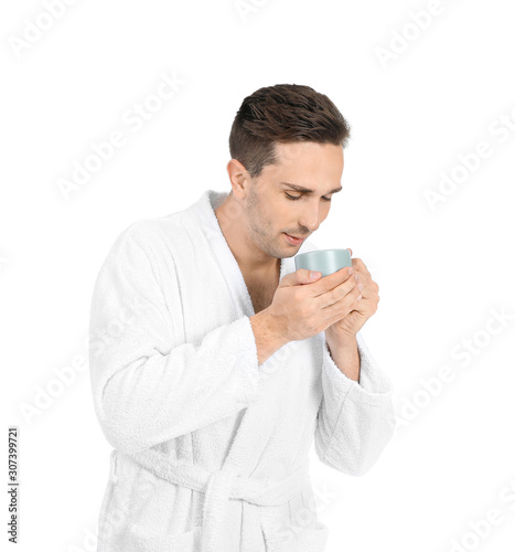 Handsome man in bathrobe and with cup of coffee on white background