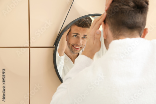 Handsome man near mirror in bathroom