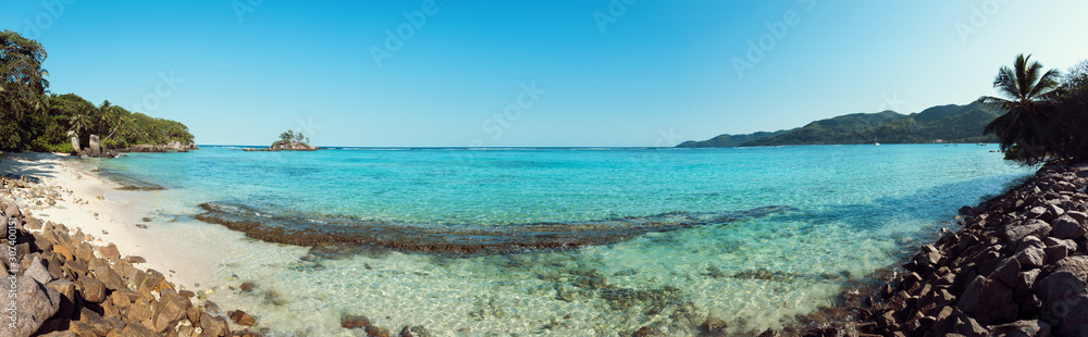 A stunning wide panoramic large format photograph of The stunning Anse royal beach in the seychelles, island of mahe. Paradise and beautiful blue sky. A stunning wide panoramic large format photograph of The stunning Anse royal beach in the seychelles, island of mahe. Paradise and beautiful blue sky.