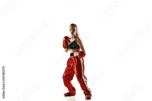 Young female kickboxing fighter training isolated on white background. Caucasian blonde girl in red sportswear practicing in martial arts. Concept of sport, healthy lifestyle, motion, action, youth. © master1305