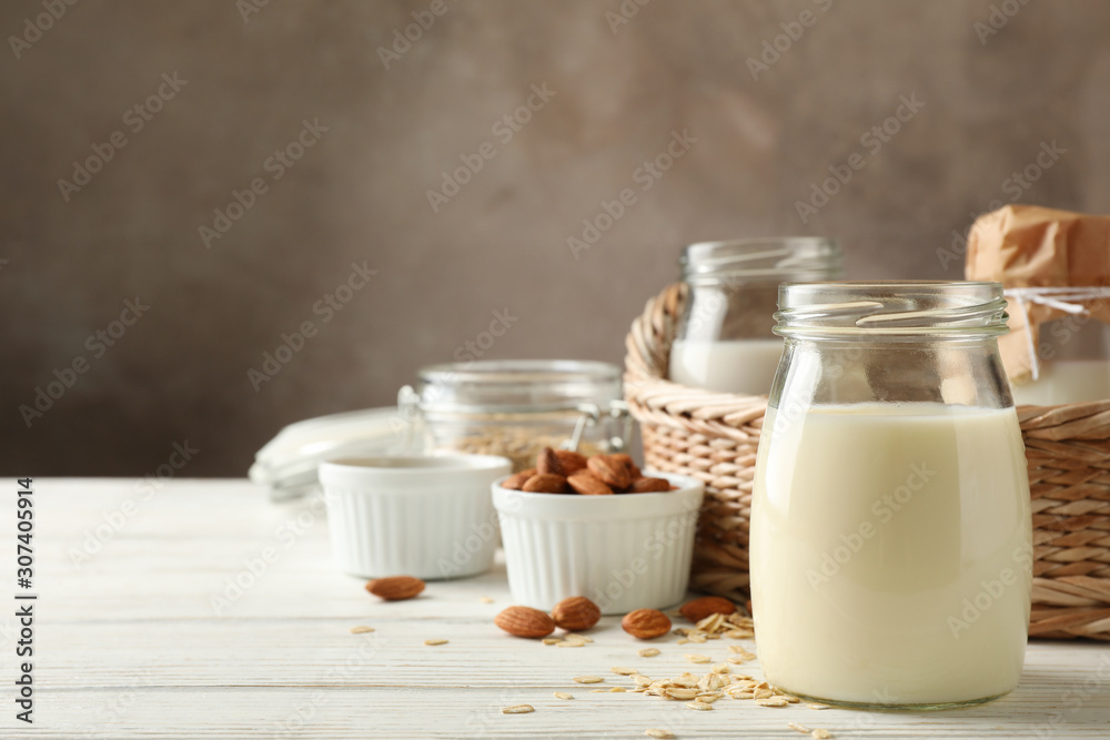 Bottle of oat milk, basket with a glasses of different types milk on wooden background, space for text Bottle of oat milk, basket with a glasses of different types milk on wooden background, space for text