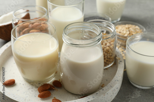 Bottle and glass of different types milk on grey background, space for text. Top view, closeup