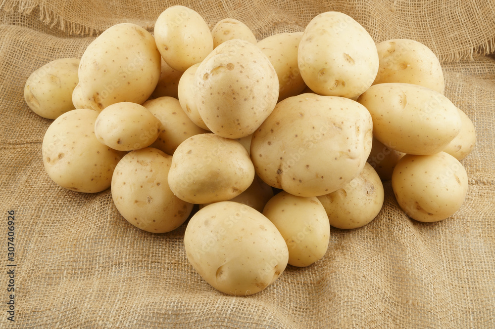 Raw potatoes on burlap sack background Raw potatoes on burlap sack background