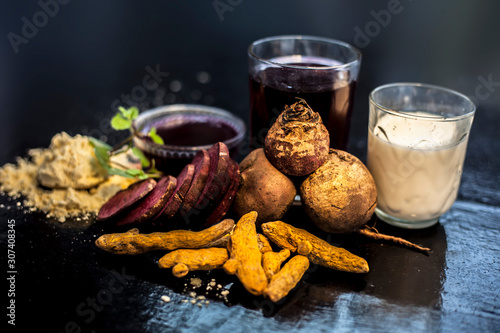 Beetroot face mask on the black glossy surface consisting of some beetroot juice, gram/chickpea flour, turmeric or Haldi, and milk. This is a comprehensive beetroot face mask. Horizontal shot. photo