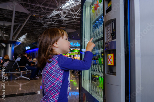 Foto Moscow Vnukovo Airport 02082019: little child girl chooses a drink in the vendin