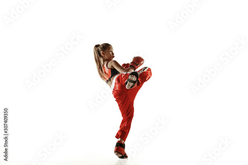 Young female kickboxing fighter training isolated on white background. Caucasian blonde girl in red sportswear practicing in martial arts. Concept of sport, healthy lifestyle, motion, action, youth.