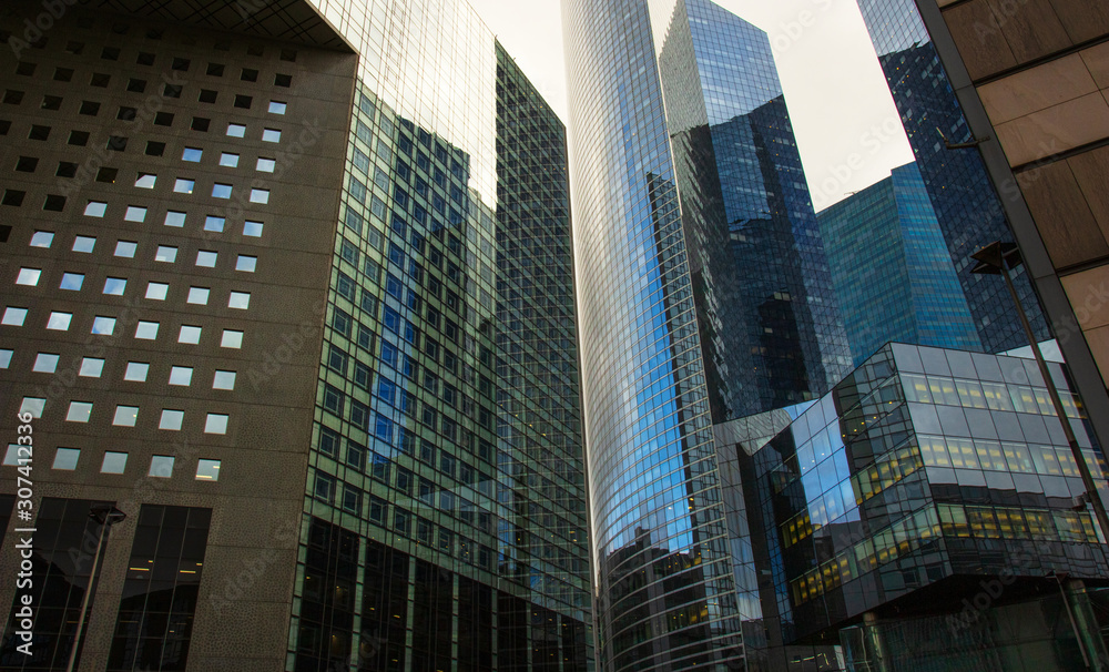 Fototapeta premium Skyscraper glass facades on a bright sunny day with sunbeams in the blue sky. Modern buildings in business district. Economy, finances, business activity concept. Bottom up view 