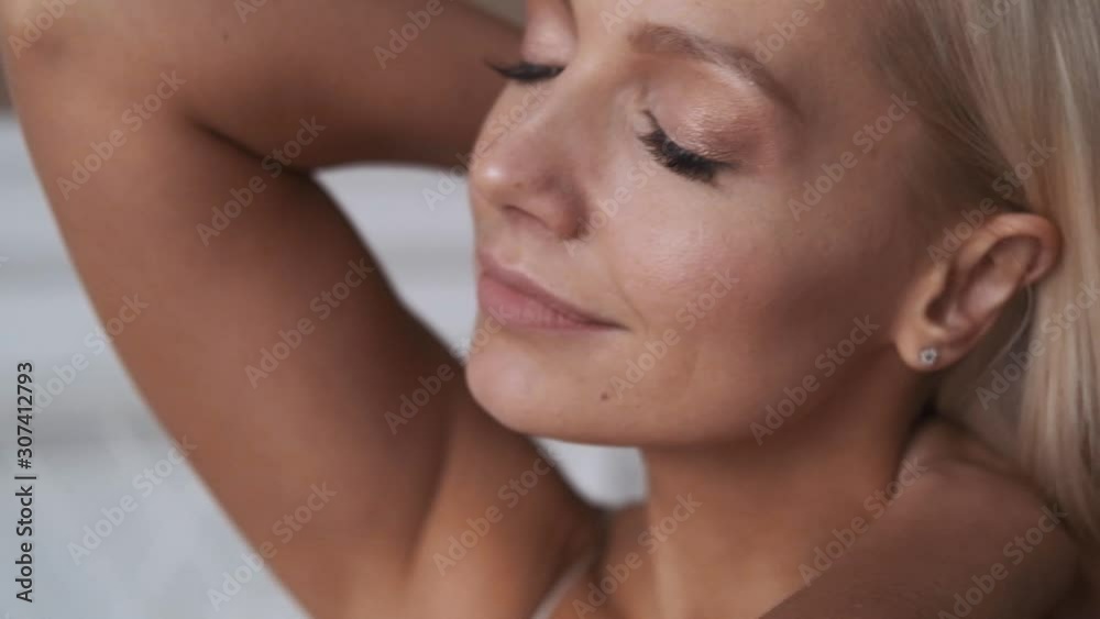 Beautiful attractive blonde girl wakes up slowly in the morning, stretches herself and smiles