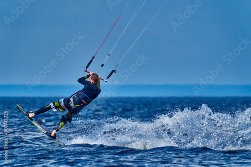 A male kiter slides on the surface of the water. Splashes of water fly apart. Close-up.