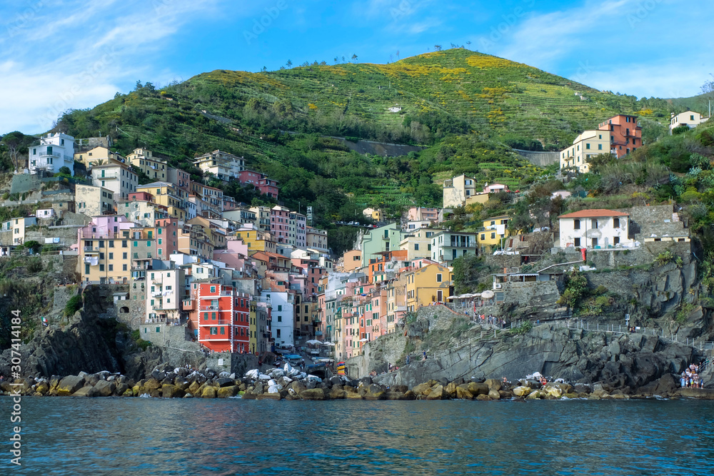Riomaggiore with colorful houses on a warm sunny day. Riomaggiore is one of the five famous coastal village in the Cinque Terre National Park, Liguria, Italy.