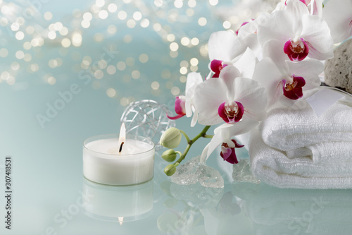 Christmas or spa decoration with white  an orchid, soft towel, burning candle on light background.